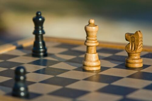 Detailed view of chess pieces on a classic wooden chessboard outdoors.