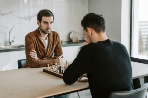 Two men play an intense chess match indoors, highlighting focus and strategy.
