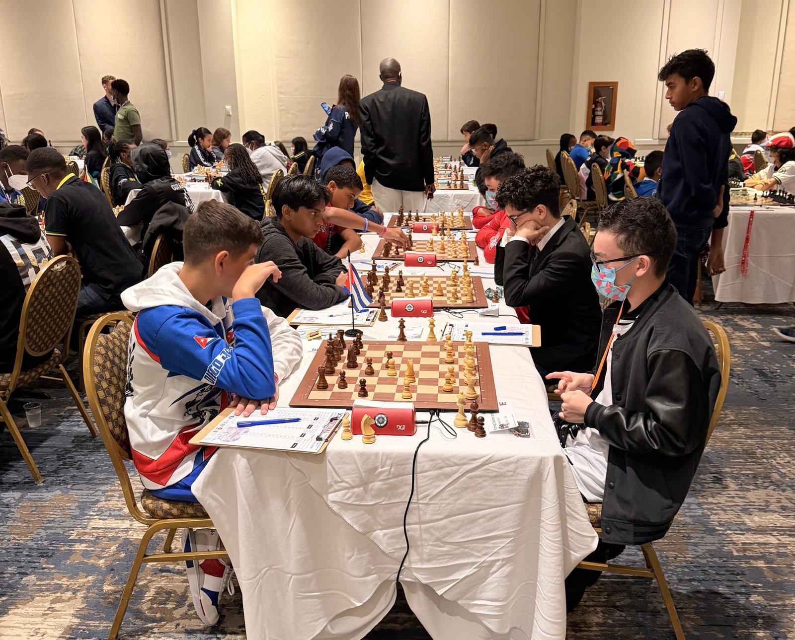 Dos jugadores puertorriqueños en mesas contiguas durante la última ronda del Festival Centroamericano y del Caribe en Dorado; sobre una de las mesas hay una banderita de Cuba.