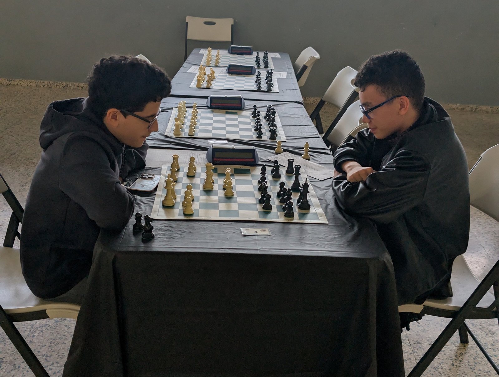 Dos jóvenes ajedrecistas frente a frente en una mesa larga durante el Campeonato Nacional Por Edades de Puerto Rico 2025, categoría Sub-14.